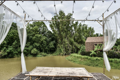 Chairs and table by lake against sky