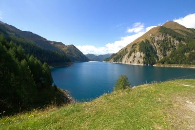 Scenic view of lake and mountains against blue sky