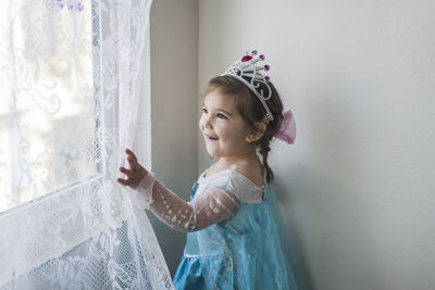 Side view of a smiling girl standing against wall