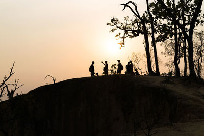 Silhouette people standing by tree against sky during sunset