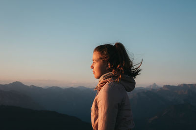 Woman standing on mountain against clear sky during sunrise