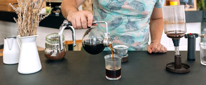 Midsection of woman holding wineglass on table
