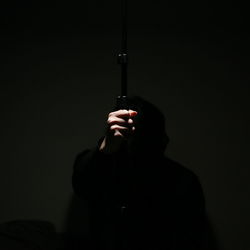 Midsection of person holding mobile phone against black background