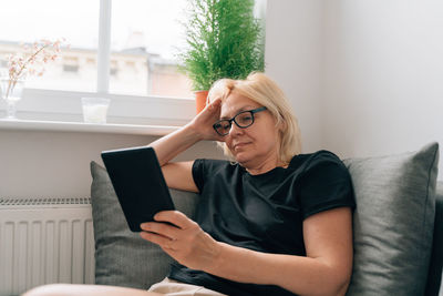 Young woman using laptop while sitting on sofa at home