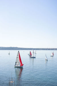 Sailboats in sea against clear sky