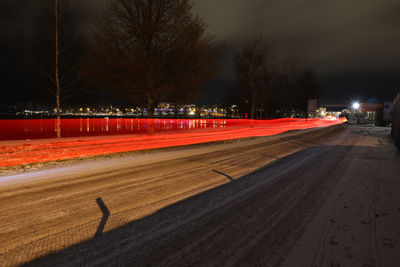 Light trails on road against sky at night