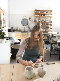 Portrait of a young woman at the ceramic studio. professional potter sculpts a mug out of clay.