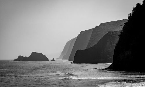 Rock formation in sea against clear sky