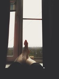 Low section of man relaxing against window