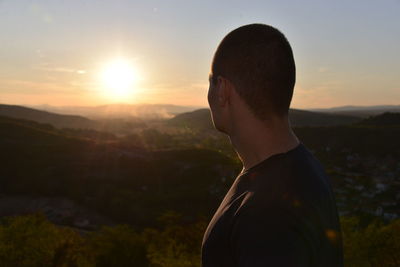 Close-up of man standing on mountain against sky during sunset