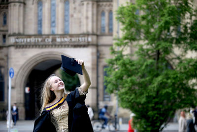 Portrait of young woman standing against building