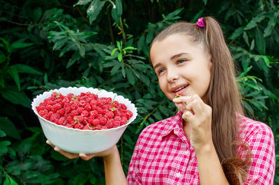 Smiling girl holding fruit in bowl