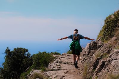 Rear view of man walking on mountain road against sky