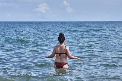 Rear view of shirtless man in sea against sky