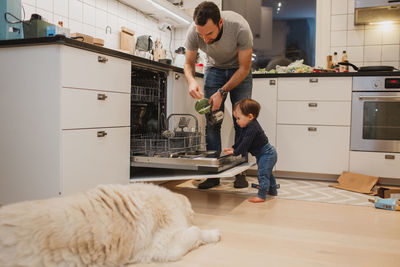 Father with toddler putting dishes into dishwasher