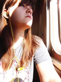 Close-up of young woman listening music while traveling in train