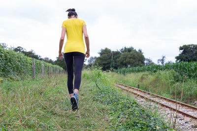 Crop sportswoman strolling near railway tracks during outdoor workout