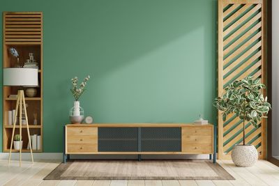 On a green color wall background, a modern living room decor with a tv cabinet.3d rendering