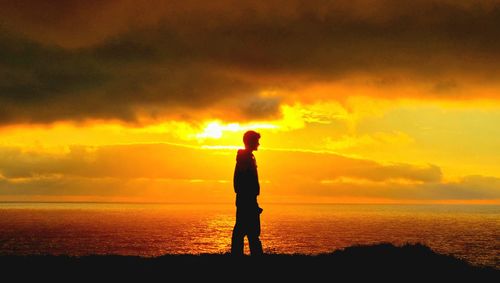 Silhouette of man standing on beach during sunset