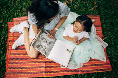 Beauiful young female teaching a beautiful child in the green field.