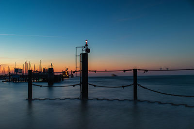 Silhouette pier over sea against clear sky during sunset