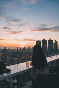 Rear view of woman looking at city buildings against sky