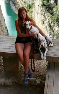 Full length portrait of young woman with dogs on seat