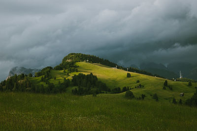 Mountain meadow at sunset against dark sky with storm clouds