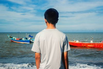 Rear view of man looking at sea against sky