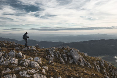 Man standing on rock against sky