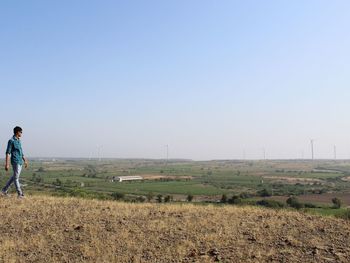 Full length of man walking on field against clear sky