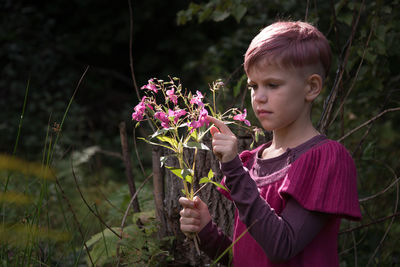 Cute girl holding pink flowering plants