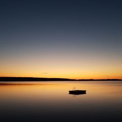 Silhouette boat in sea against sky during sunset