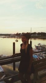 Portrait of young woman standing on river against sky