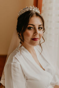 Portrait of young woman standing against wall
