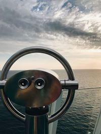 Close-up of coin-operated binoculars against sea