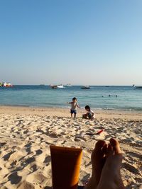 People on beach against clear sky