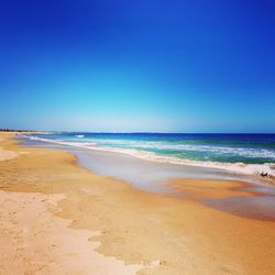 Scenic view of beach against clear blue sky