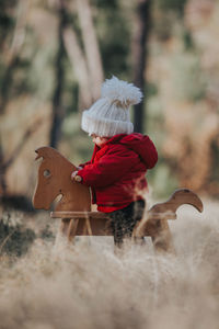 Baby girl sitting on rocking horse during winter