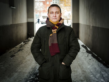 Mature man standing amidst buildings during winter