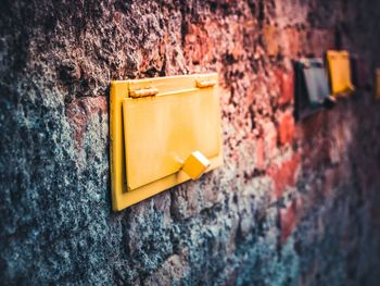 Close-up of yellow mailbox on wall