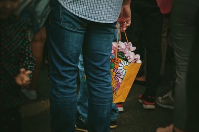 Midsection of man holding bag with flowers