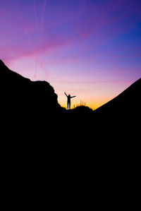 Silhouette person standing on mountain against sky during sunset