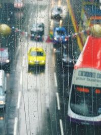 Cars on road seen through wet window in rainy season