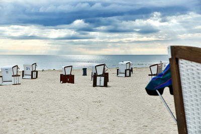 Chairs on beach by sea against sky