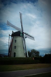 Low angle view of traditional windmill against cloudy sky