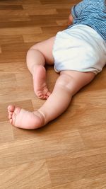 Low section of baby feet on floor at home