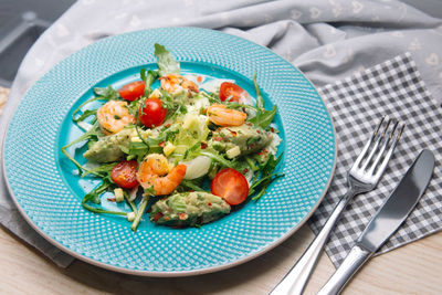 Shrimps salad with guacamole sauce, arugula, spices and chopped cherry tomatoes