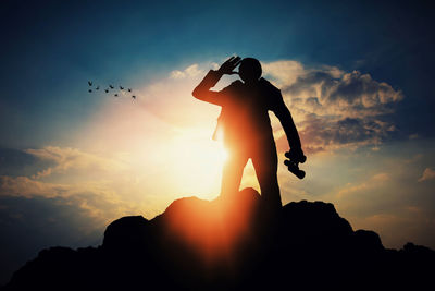 Silhouette man standing against sky during sunset