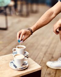 Midsection of person holding coffee cup on table